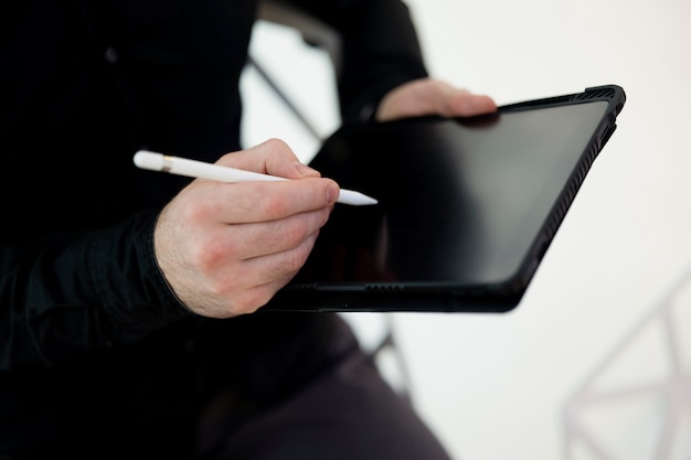 Copie a tela de espaço do tablet. Feche a foto de mãos masculinas, assinando no gadget usando a caneta. Corte a visão do homem com roupas escuras. Não assine faturas eletrônicas de maneira imprudente! Conceito de educação financeira.