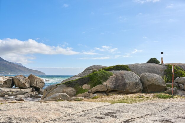 Copie as rochas do mar e do oceano do espaço em uma praia remota, tranquila e serena em um relaxante destino costeiro tropical com fundo de montanha Seascape céu azul e água das marés em ilha isolada no exterior