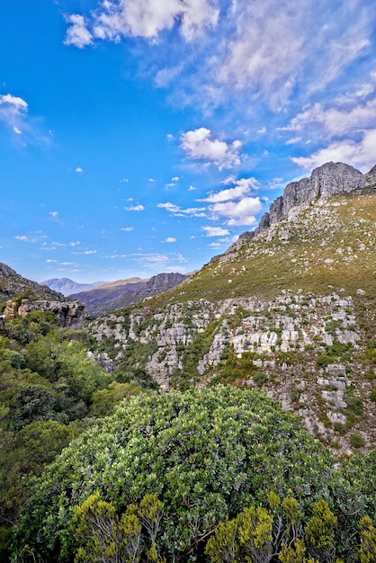 Copie el espacio con el paisaje de montaña contra un fondo de cielo azul nublado en Ciudad del Cabo Hermoso y tranquilo paisaje de exuberantes plantas y árboles verdes alrededor de un majestuoso valle rocoso en un día soleado en la naturaleza