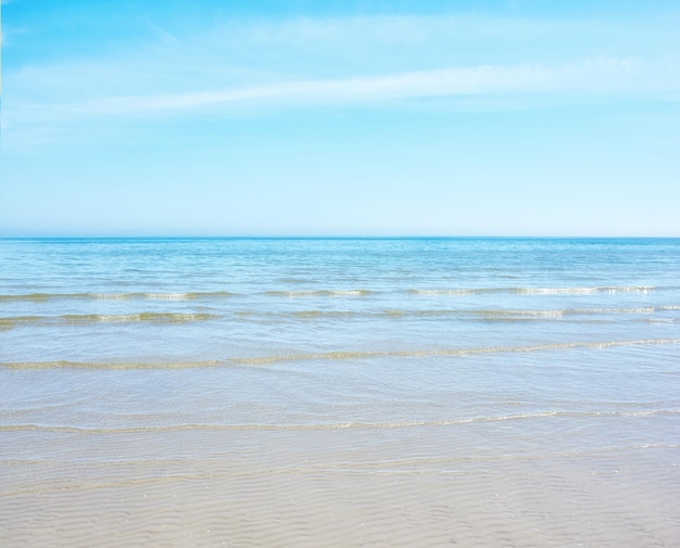 Copie el espacio en la playa con un fondo de cielo azul sobre el horizonte Olas tranquilas del océano a través de un mar vacío a lo largo de la orilla arenosa Paisaje pacífico y tranquilo para unas vacaciones de verano relajantes y zen