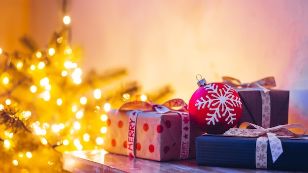 Copie o espaço com os presentes em foco seletivo no fundo das luzes do bokeh da árvore de Natal