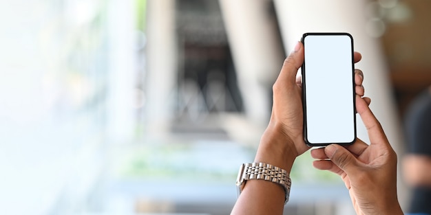 Copie o homem espaço segurando um smartphone de tela em branco branco. Mãos segurando móvel