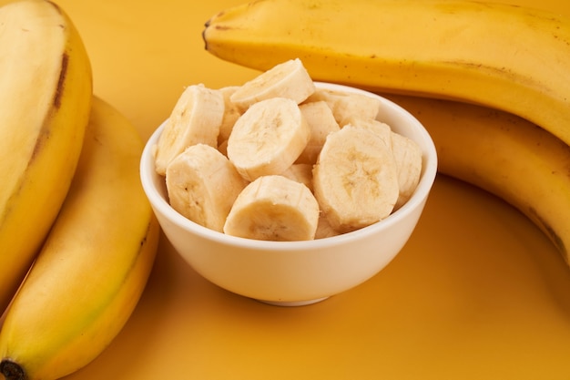 Copo branco com bananas fatiadas em um amarelo