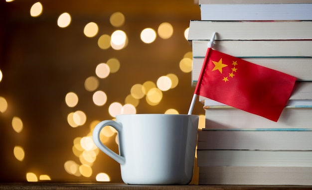 Copo branco com bandeira da China perto de livros