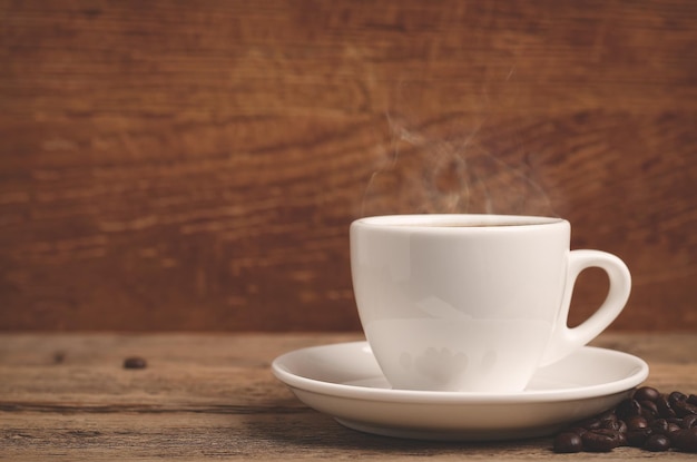 Copo branco com café quente na mesa de madeira