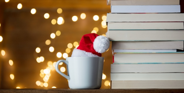 Copo branco com chapéu de natal e livros