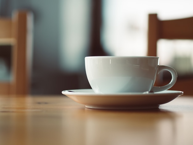 Foto copo branco do café quente servido na mesa de madeira no café.