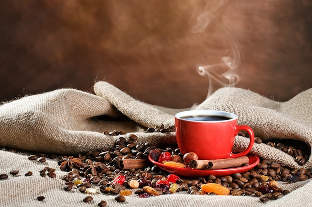 Copo cerâmico vermelho com café quente em placas de madeira.