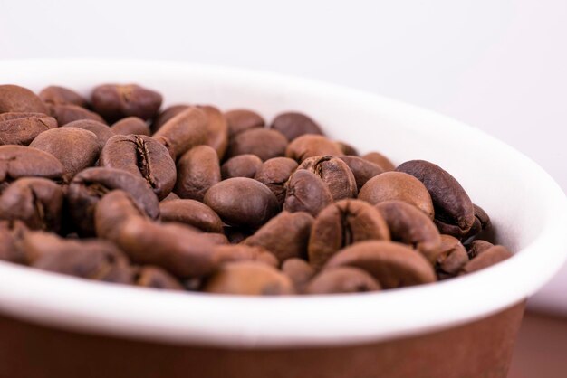 Copo cheio de grãos de café na mesa closeup