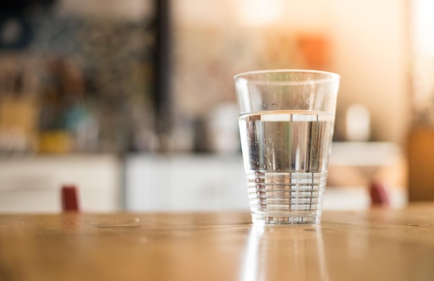 Copo claro de água fria fresca na mesa da cozinha