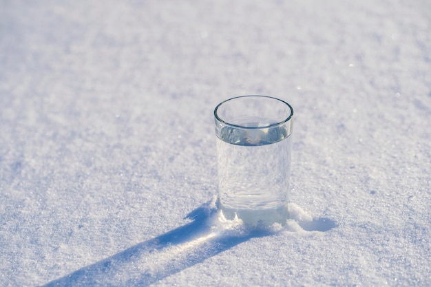 Copo com água em uma neve branca no inverno
