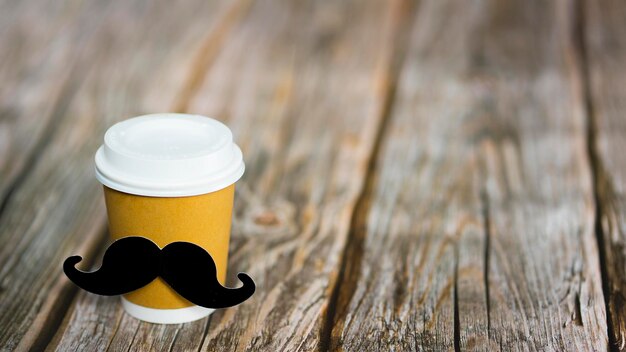 Copo com café com bigode sobre fundo de madeira Imagem com foco seletivo