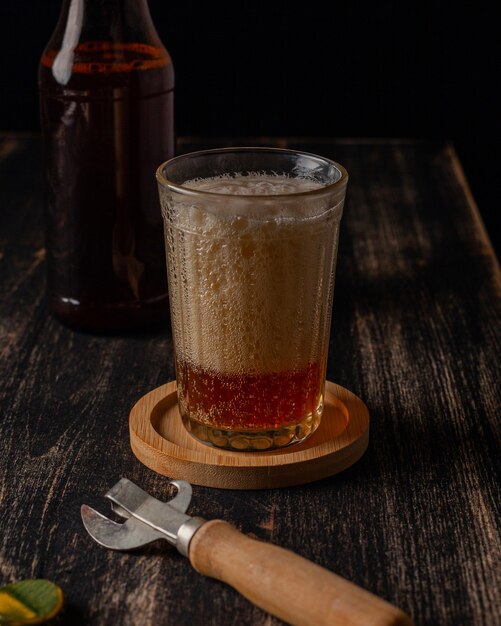 Copo com cerveja e uma garrafa de cerveja em uma mesa escura