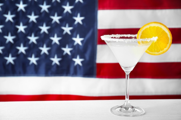 Copo com coquetel alcoólico na mesa contra o fundo da bandeira americana