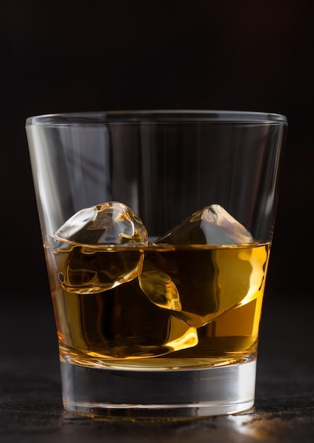 Copo com cubos de gelo de whisky escocês no preto, Macro