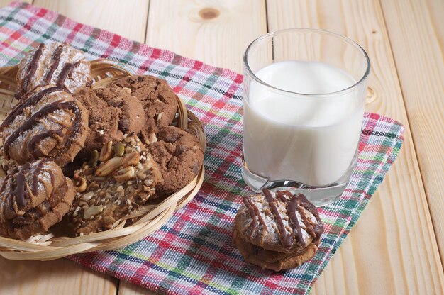 Copo com leite e biscoitos diferentes em uma mesa de madeira