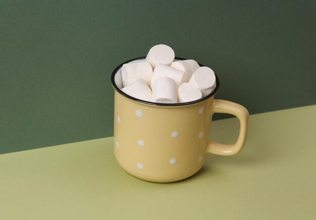 Copo com marshmallows em um fundo verde de dois tons Minimal still life