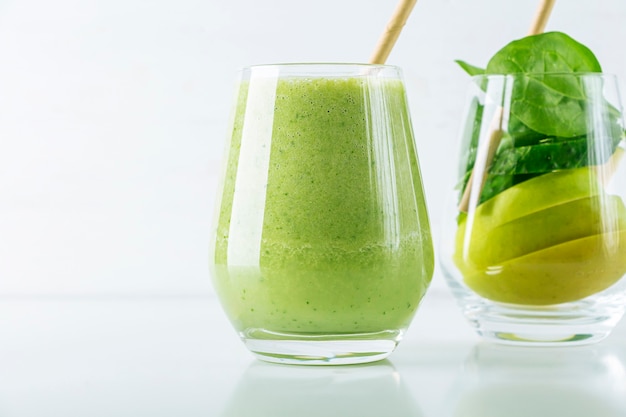 Copo com smoothie verde e copo com ingredientes, espinafre, maçã, pepino