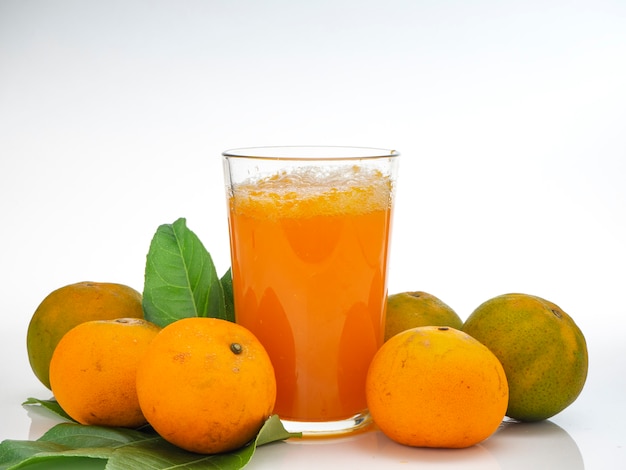 Copo com suco de laranja e frutas com folhas verdes