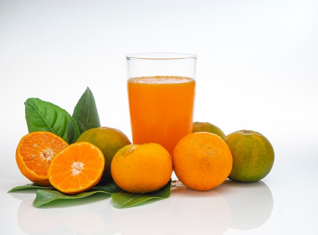 Copo com suco de laranja e frutas com folhas verdes