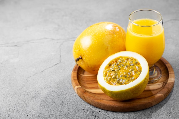 Copo com suco de maracujá e maracujá fatiado em cima da mesa