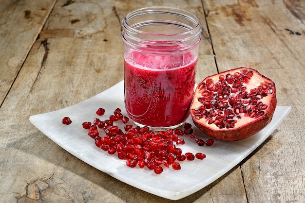 Copo com suco de romã e frutas de romã em um prato