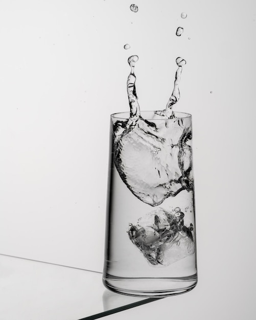 Copo de água com gelo em uma mesa de vidro