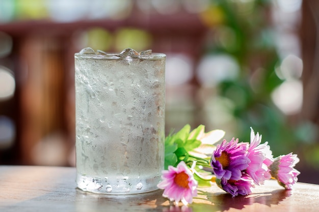 copo de água e flor falsificada na mesa de madeira