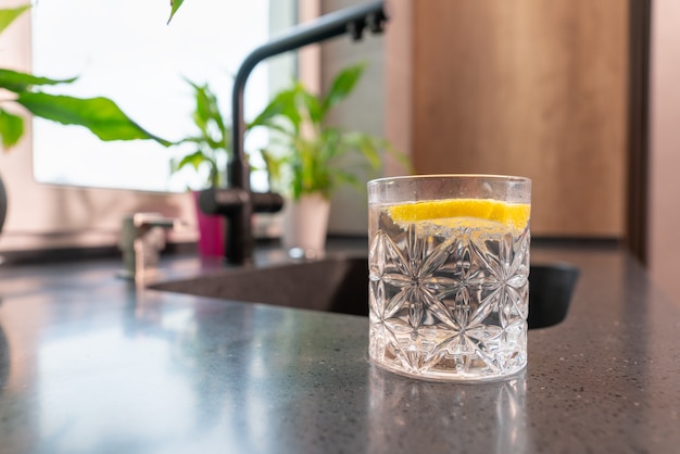 Copo de água refrescante com uma fatia de limão picante em uma visão de baixo ângulo em uma bancada em uma cozinha com copyspace