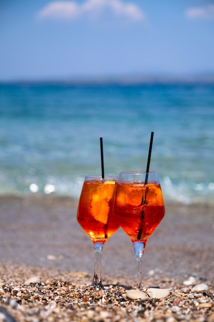 Copo de aperol spritz de coquetel na areia perto do mar