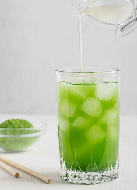 Copo de bebida refrescante matcha latte feita de folhas de chá verde em pó com leite na mesa