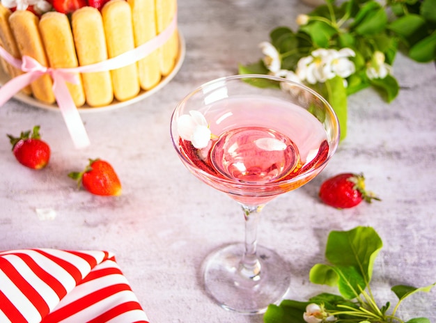 Copo de bolo de coquetel rosa com morangos frescos com ramo de flores de macieira conceito de casal data romântica de casamento ou dia dos namorados