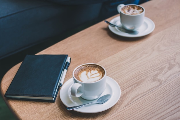 Copo de café com caderno no fundo da mesa de madeira com filtro vintage