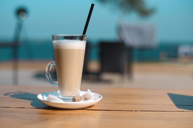 Copo de café com canudo preto na mesa de madeira