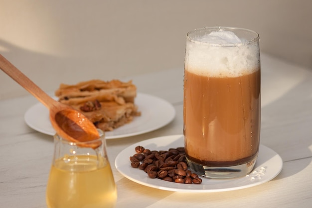 Copo de café com espuma de leite com mel na mesa de madeira branca.