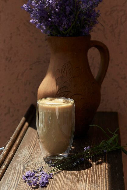 Copo de café com leite e flores de lavanda do lado de fora no terraço do café Tempo de pausa para o café atmosférico Sombras duras