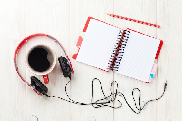 Copo de café de fones de ouvido e bloco de notas na mesa