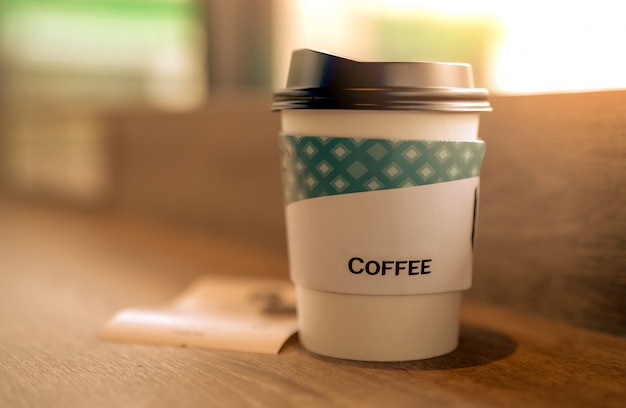 Copo de café de papel na cafeteria na mesa de madeira marrom