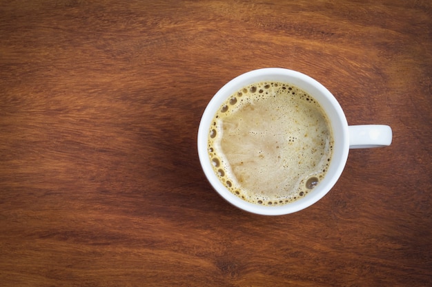 Copo de café de vista superior em fundo de madeira