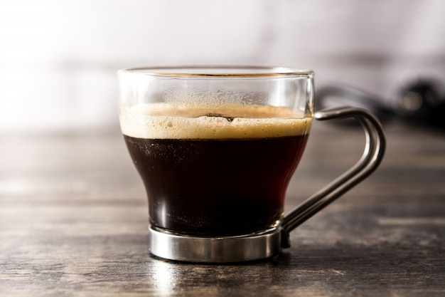 Foto copo de café e grãos de café na mesa de madeira.