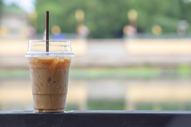 Copo de café expresso frio na haste de aço Árvore embaçada de fundo e água