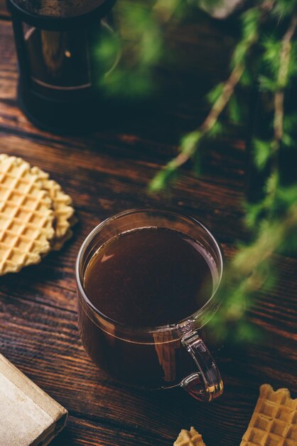 Copo de café feito na imprensa francesa com waffles na mesa de madeira rústica Vista de alto ângulo