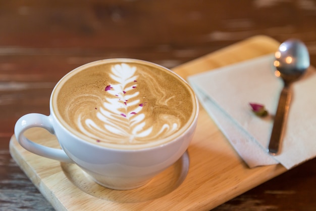 Copo de café latte em prato de madeira