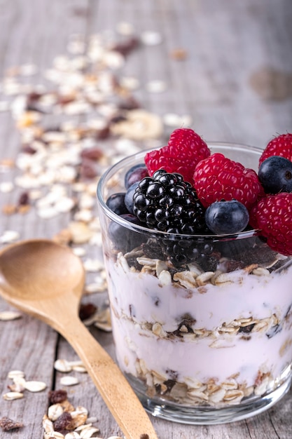 Copo de cereal com frutas da floresta, sobre uma base de madeira. conceito de café da manhã saudável