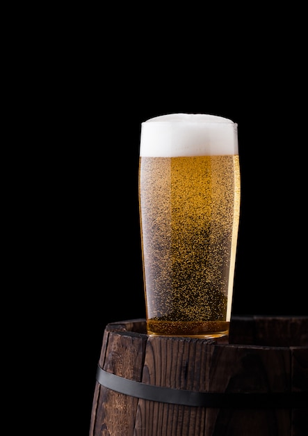 Copo de cerveja artesanal no barril de madeira velho em fundo preto