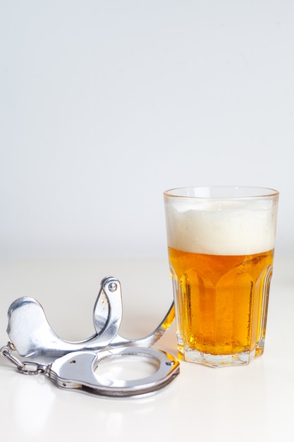 Copo de cerveja com algemas como símbolo de abuso de álcool