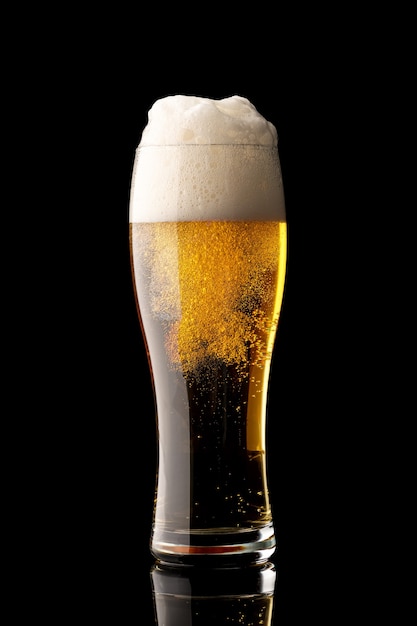 Copo de cerveja com bolhas e espuma espessa branca, isolado em fundo preto