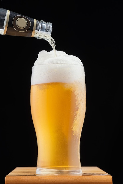 Foto copo de cerveja com espuma no fundo preto