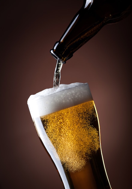 Foto copo de cerveja e garrafa em um marrom