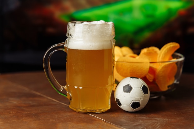 Foto copo de cerveja e lanche em um fundo de tv de jogo de futebol